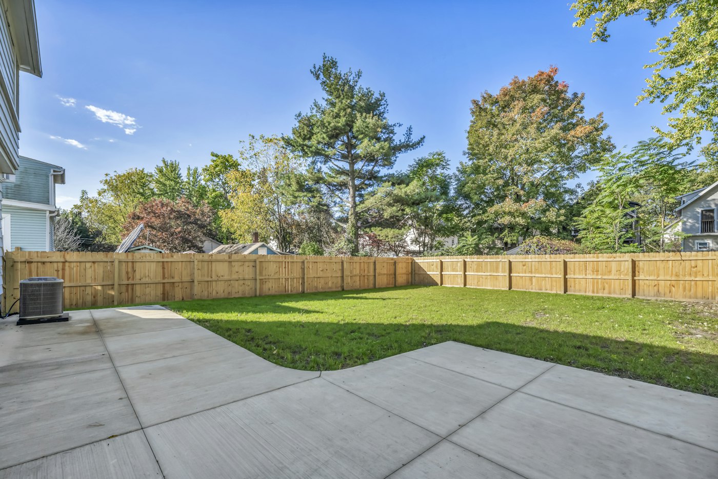 New concrete patio beside a backyard lawn and fence