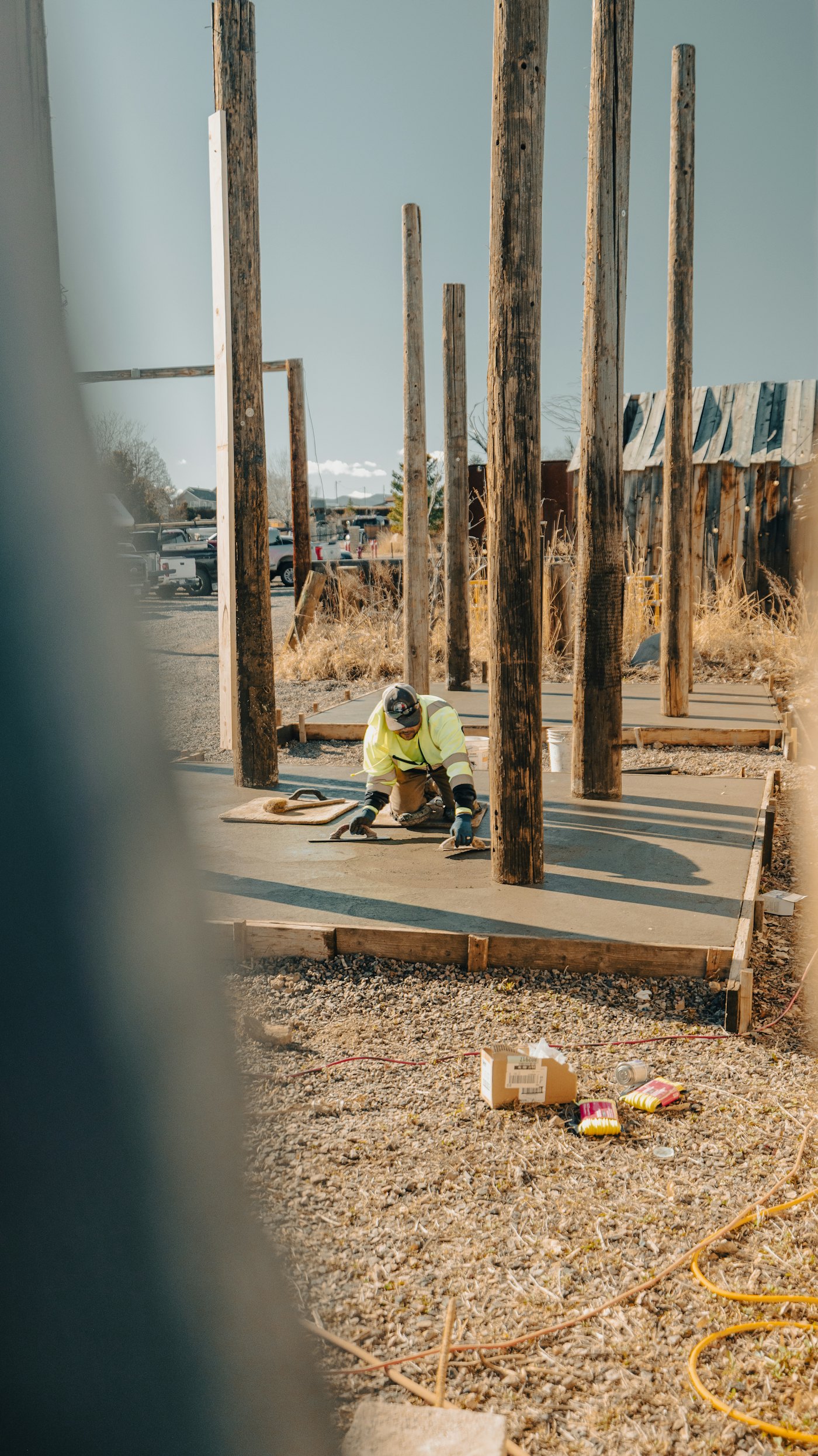 Concrete finisher troweling a fresh slab between framing posts